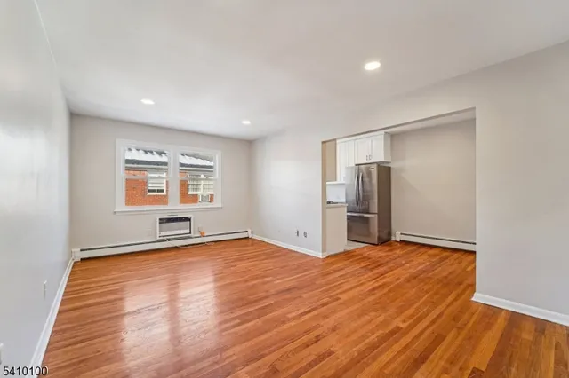 a view of an empty room with a window and wooden floor