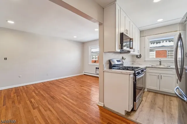 a kitchen with granite countertop wooden floors and white stainless steel appliances