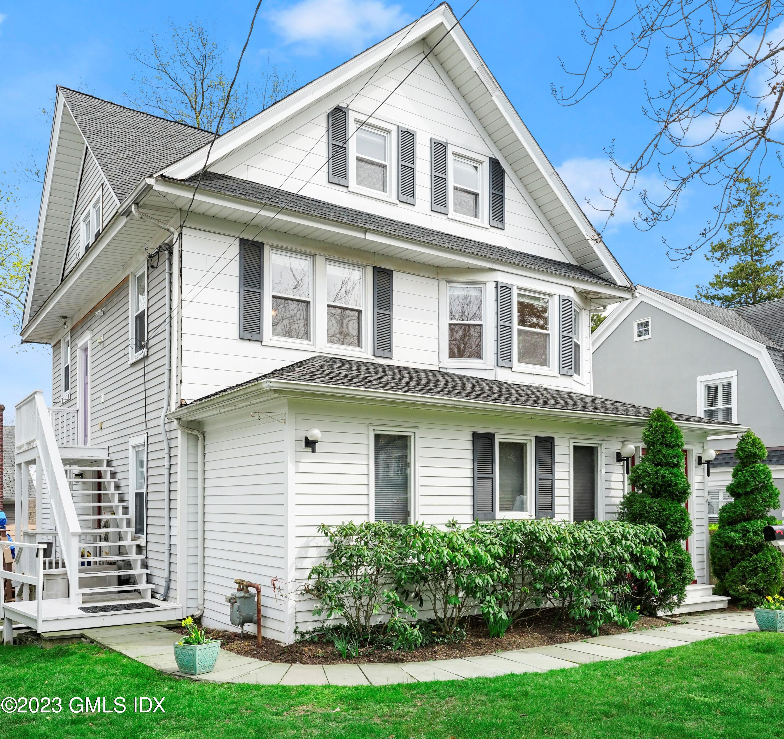 a front view of a house with a yard and potted plants