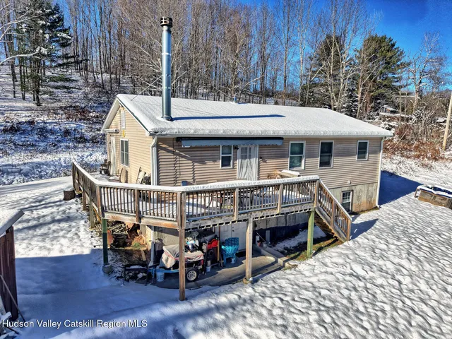 a view of a house with a wooden deck and furniture