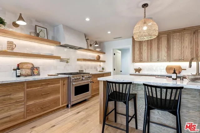 a kitchen with stainless steel appliances granite countertop a stove a sink dishwasher and a dining table with wooden floor