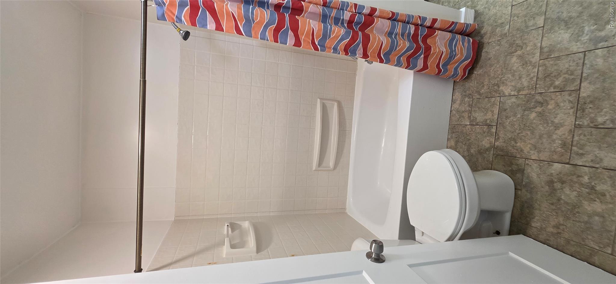 4363 West Dodge Road Clio, MI 48420 - Photo 20 of 52 White bathtub with integrated shower, white subway tile surround, and neutral-toned tile flooring