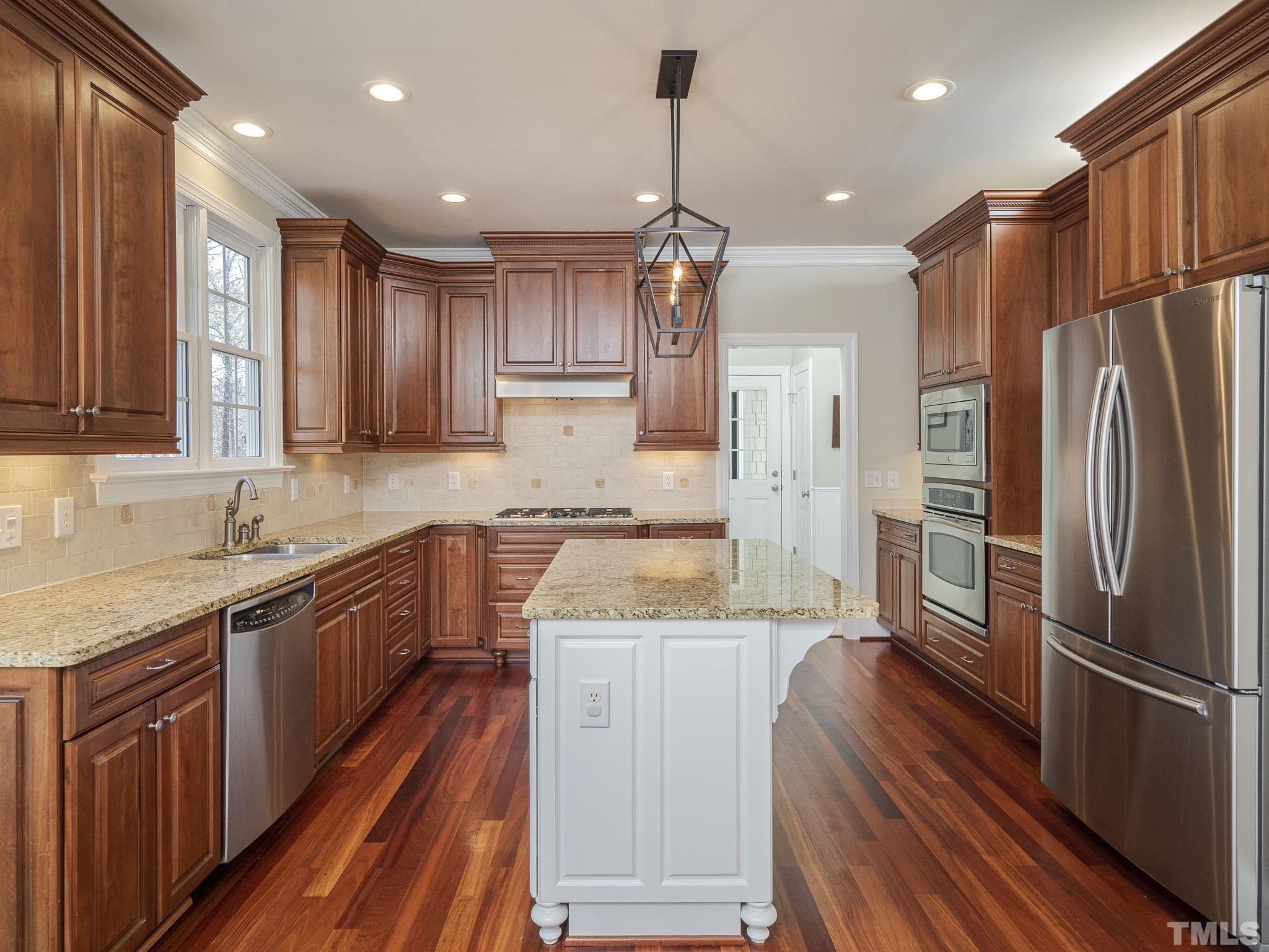 7112 Anglesey Court Wake Forest, NC 27587 - Photo 9 of 23 a kitchen with stainless steel appliances granite countertop a refrigerator a sink dishwasher a stove and white countertops with wooden floor