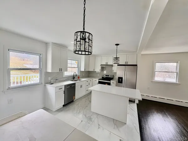 a kitchen with stainless steel appliances kitchen island granite countertop a stove a sink dishwasher and a refrigerator
