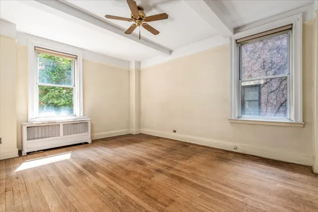 a view of an empty room with a window and wooden floor