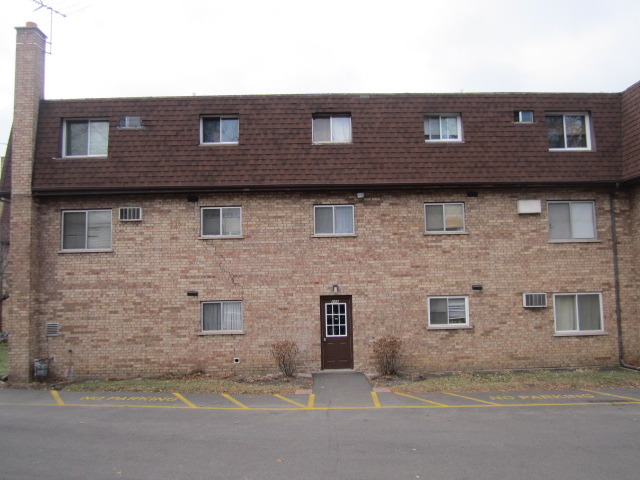 115 East Dundee Road, Unit 2N Wheeling, IL 60090 - Photo 16 of 16 a brick house with a small yard and parking space
