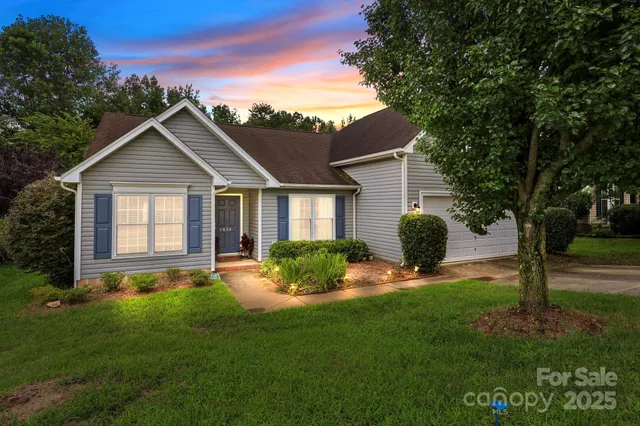 a backyard of a house with table and chairs plants and large tree