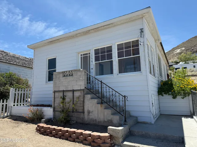 a view of a house with wooden fence next to a yard