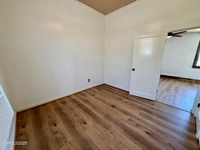 an empty room with wooden floor cabinet and windows