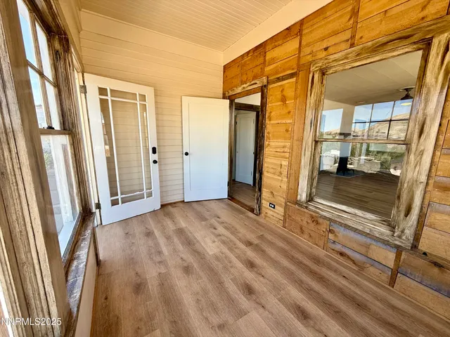 an empty room with wooden floor ceiling fan and windows