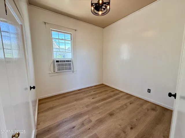 a view of empty room with wooden floor and fan