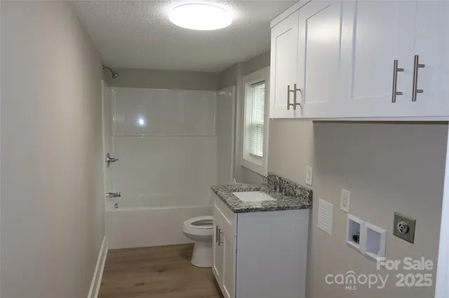 a bathroom with a granite countertop sink a toilet and shower