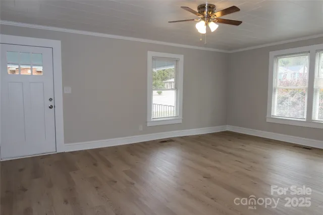 a view of an empty room with wooden floor and a window