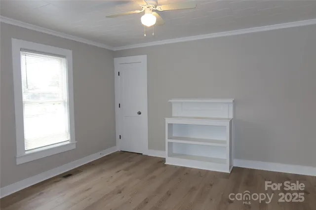 a view of an empty room with a window and wooden floor