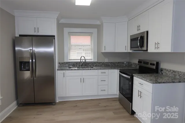 a kitchen with stainless steel appliances granite countertop a refrigerator a sink a stove a microwave and wooden cabinets