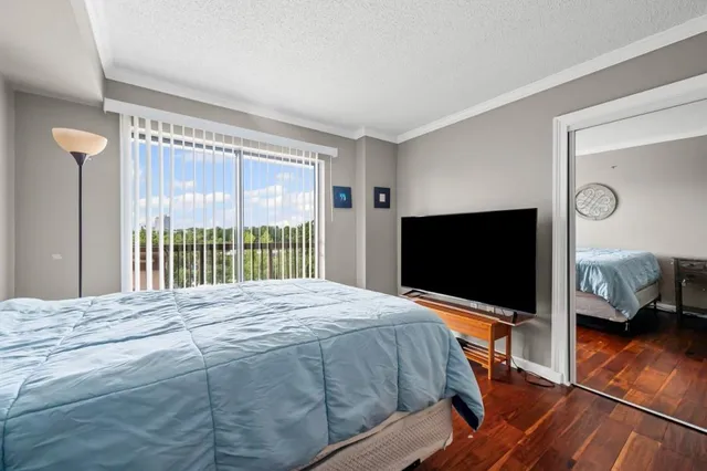 a bedroom with a bed and a flat tv screen on dresser