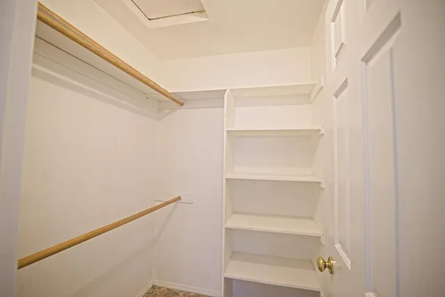 a view of walk in closet with empty racks