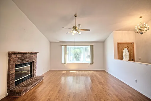 a view of a livingroom with wooden floor a fireplace and windows