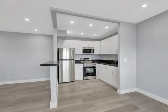 a kitchen with granite countertop white cabinets and refrigerator