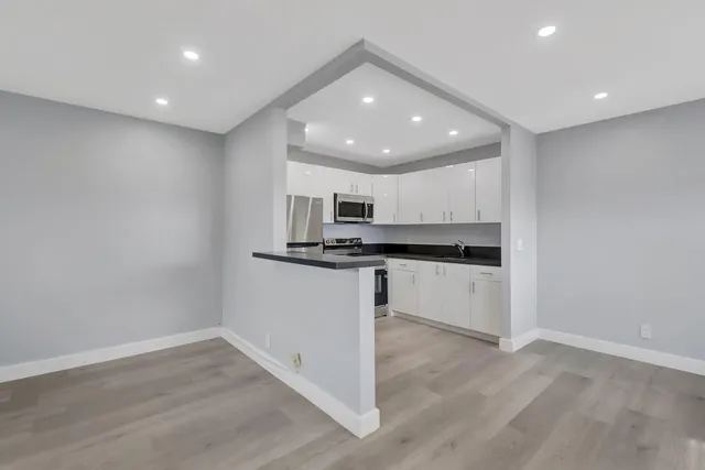 a kitchen with granite countertop white cabinets stainless steel appliances and a sink