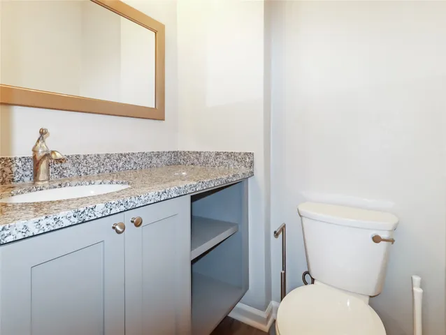 a bathroom with a granite countertop toilet sink and mirror