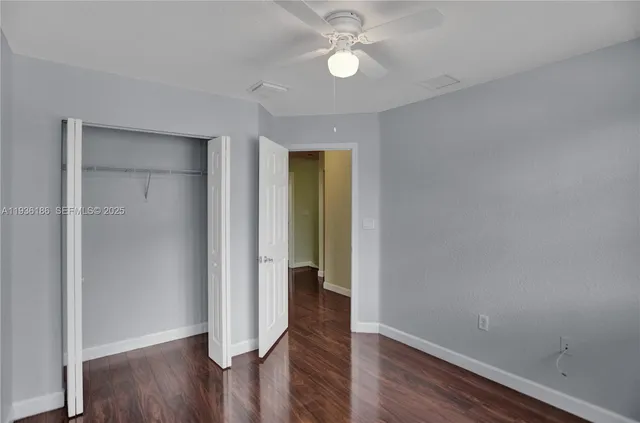 an empty room with wooden floor and a ceiling fan