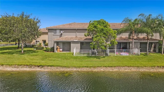a front view of a house with a garden and lake view