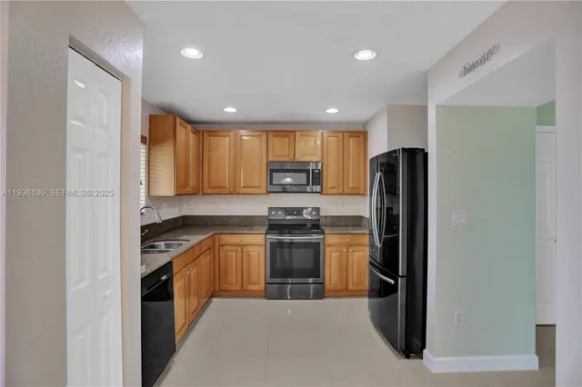 a kitchen with stainless steel appliances granite countertop a refrigerator a stove top oven a sink and dishwasher