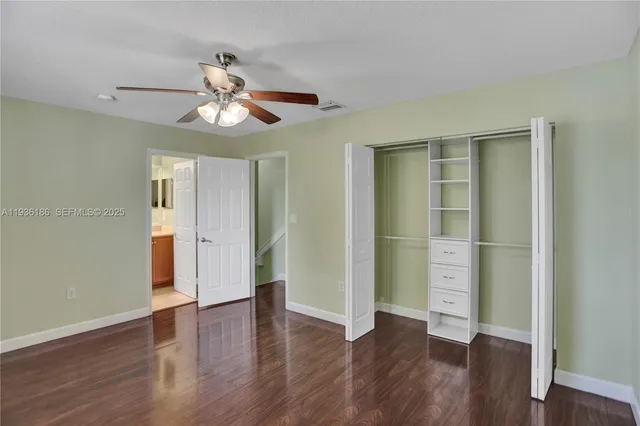 a view of an empty room with wooden floor and a ceiling fan