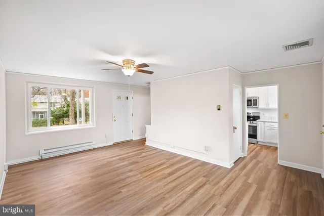 an empty room with wooden floor and windows