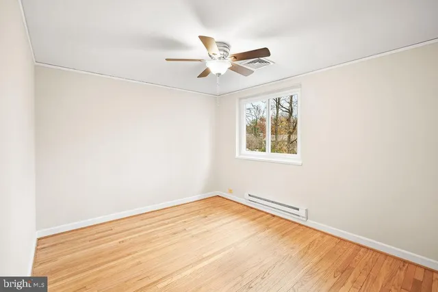 an empty room with a window and ceiling fan
