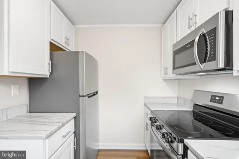 a kitchen with stainless steel appliances white cabinets and a stove top oven