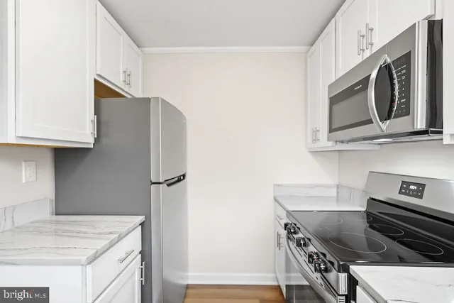 a kitchen with stainless steel appliances white cabinets and a stove top oven