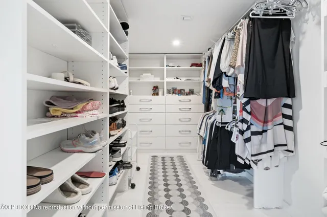 a view of walk in closet with clothes and shoes