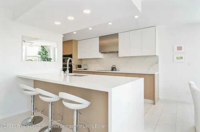 a kitchen with stainless steel appliances granite countertop a sink a stove a microwave a island with white cabinets and chairs