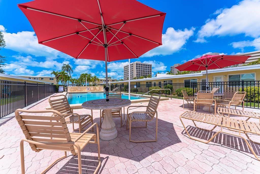 6006 Midnight Pass Road, Unit 29 Sarasota, FL 34242 - Photo 12 of 19 a view of a patio with a table and chairs under an umbrella