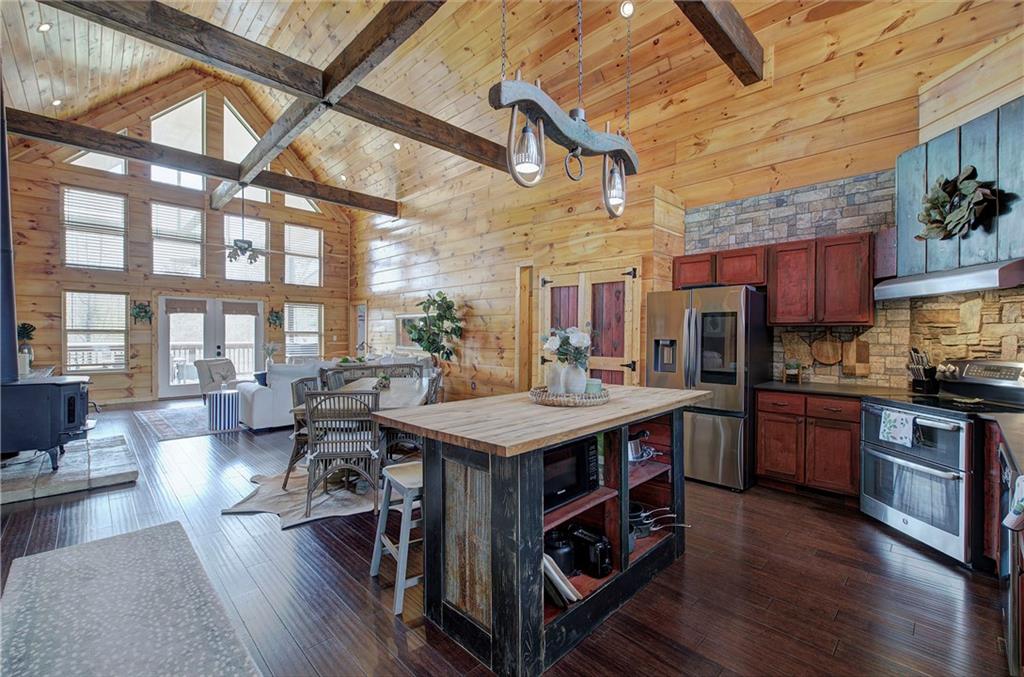 100 Buckwood Farms Path Dallas, GA 30132 - Photo 5 of 70 a large kitchen with stainless steel appliances granite countertop a stove a refrigerator a dining table and chairs with wooden floor