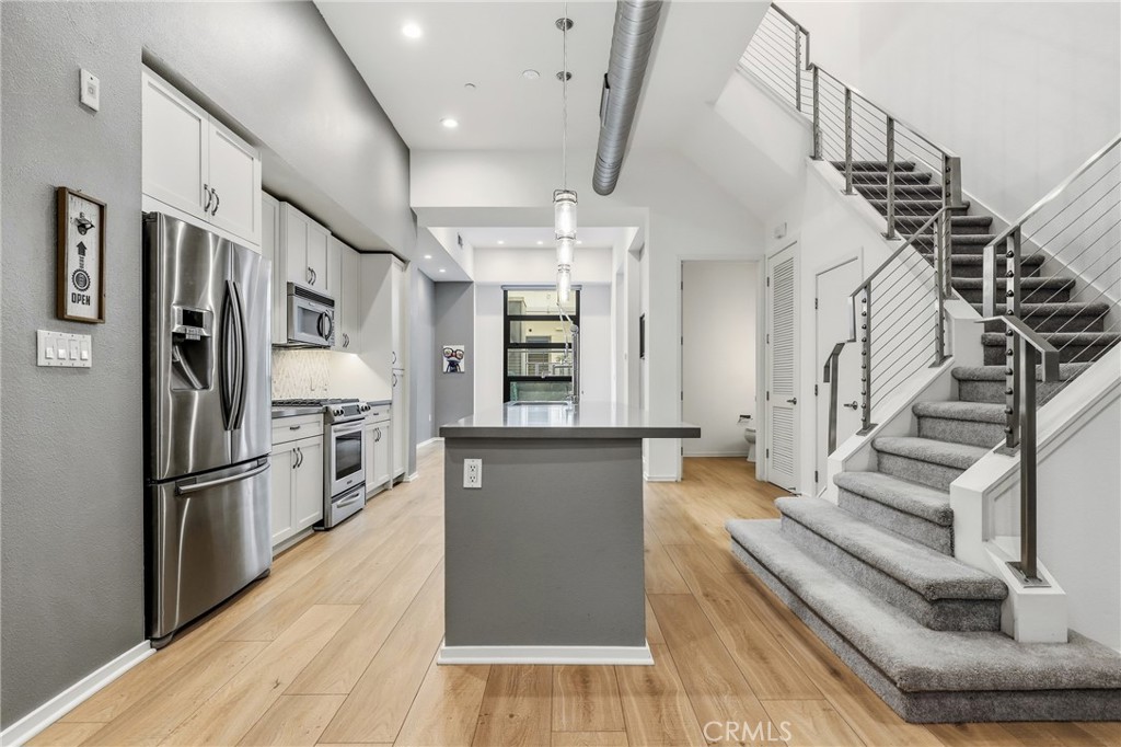 133 The Promenade North, Unit 118 Long Beach, CA 90802 - Photo 8 of 35 a kitchen with stainless steel appliances kitchen island wooden floors granite top and stainless steel appliances