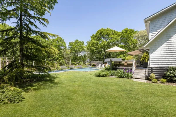 a view of a backyard with table and chairs and potted plants and large trees