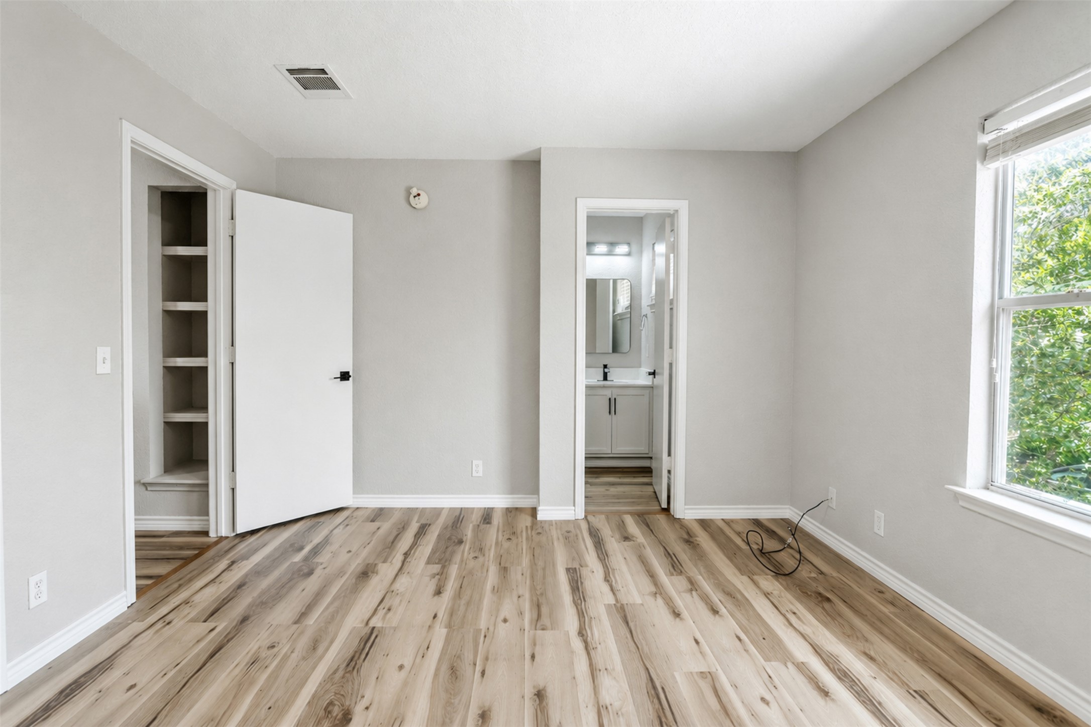 4523 Secure Lane Austin, TX 78725 - Photo 26 of 40 A tranquil bedroom features warm wood flooring and convenient en-suite bathroom access.