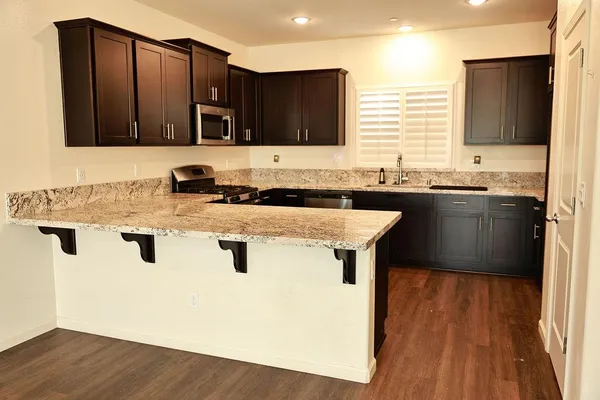 a kitchen with granite countertop a sink stove and cabinets