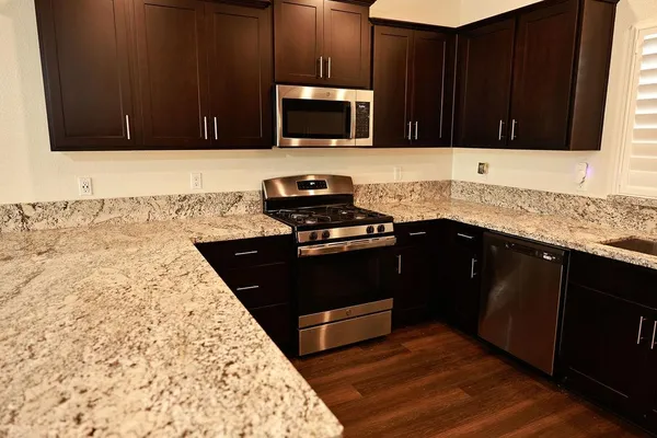 a kitchen with stainless steel appliances granite countertop wooden cabinets a stove top oven and granite counter top