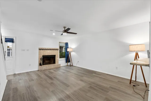 a view of an empty room with wooden floor fireplace and a window