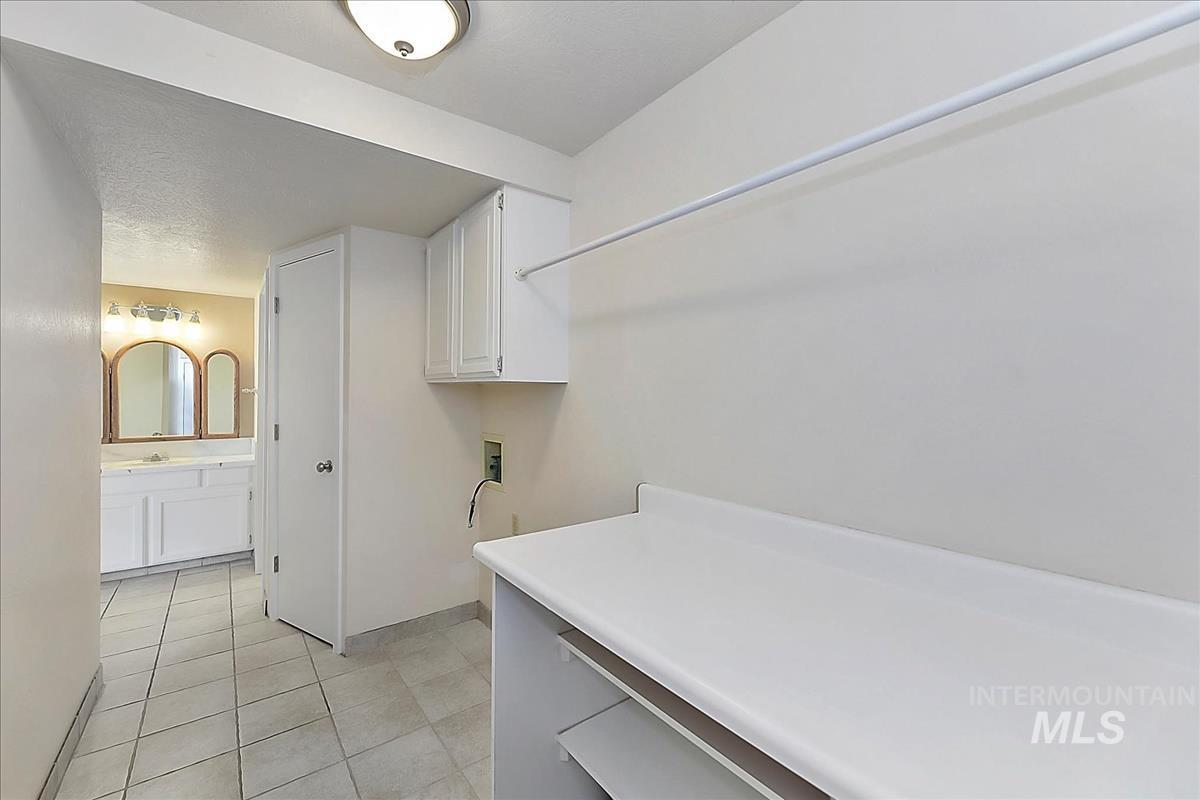 2804 West Sunrise Rim Road Boise, ID 83705 - Photo 24 of 50 Laundry area featuring a utility sink connection, wall-mounted cabinetry, and a countertop with open shelving