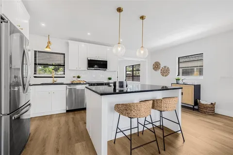 a kitchen with stainless steel appliances granite countertop a stove top oven a refrigerator a sink and a dining table with wooden floor