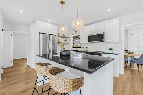a kitchen with stainless steel appliances granite countertop a kitchen island a stove a refrigerator a kitchen island a table and chairs