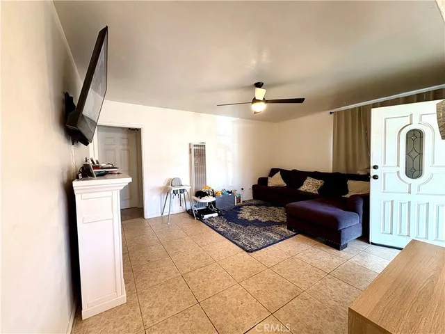 a living room with furniture a flat screen tv and a refrigerator
