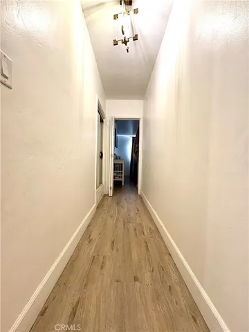 a view of a hallway with wooden floor and a chandelier