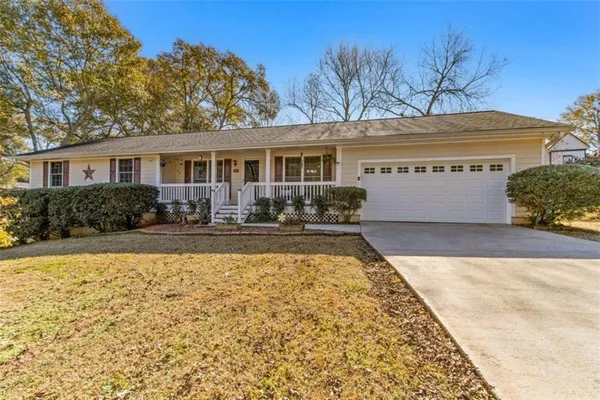 a front view of house with yard seating and covered with trees