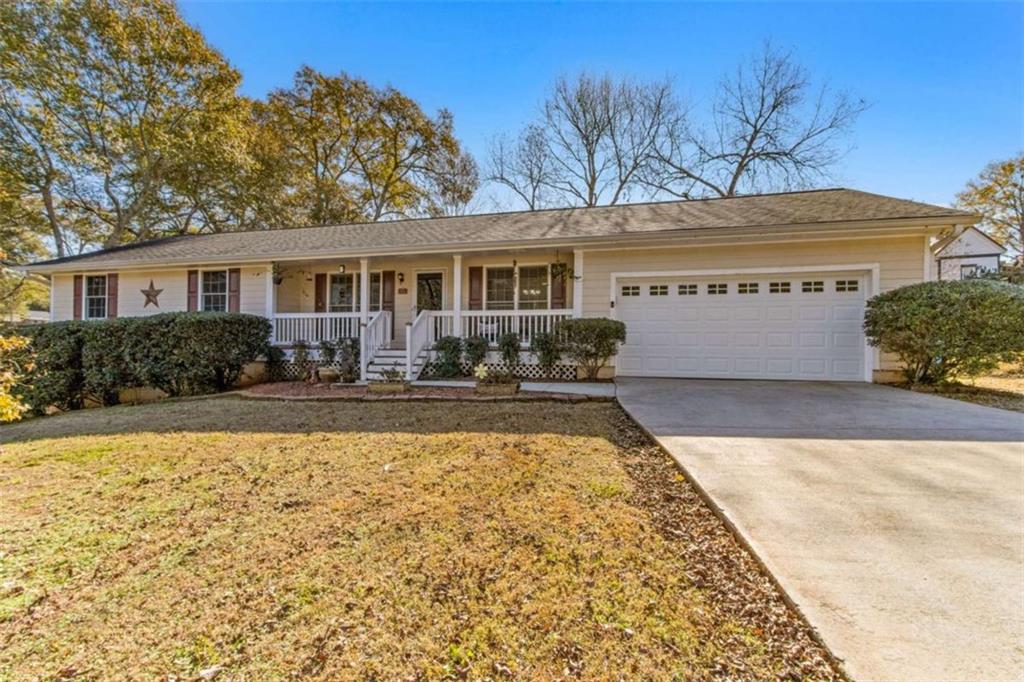 a front view of house with yard seating and covered with trees